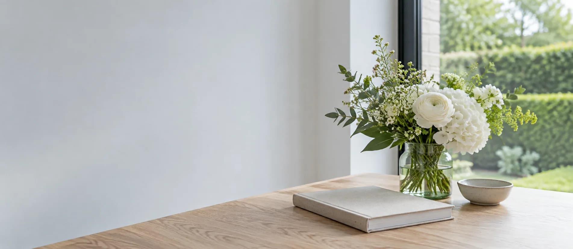 Witte bloemen en een herinneringsboek bij een raam